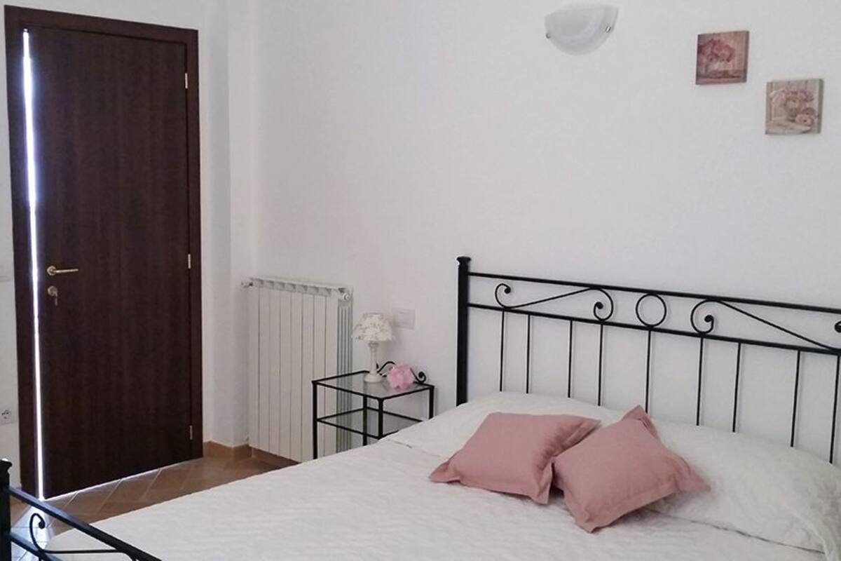 A bedroom with a bed, a wardrobe, a radiator, and a nightstand.