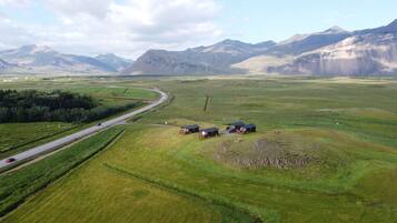 Paisatge rural amb carretera, camps verds i alguns edificis.