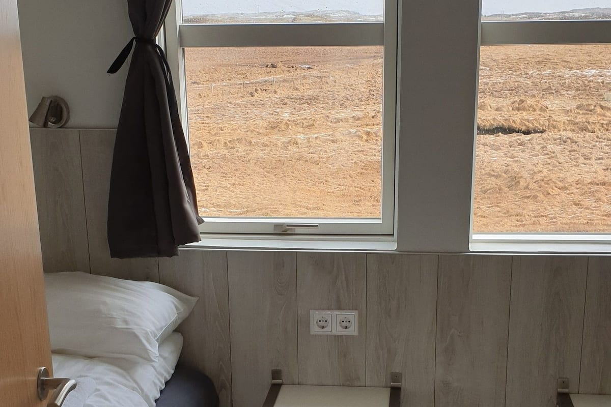 A bedroom with a bed, a window, and a radiator.