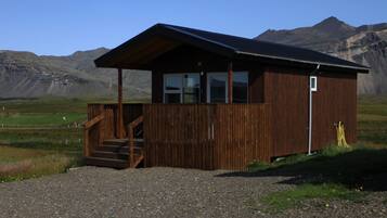 Eine Holzhütte mit Veranda und Treppe, vor einer Berglandschaft gelegen.