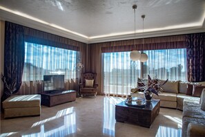 A spacious living room with a large flat-screen TV, comfortable seating, and a decorative vase on a coffee table. - Callista Luxury Residences (Ierapetra)