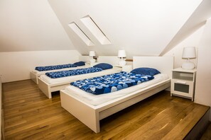 A bedroom with two beds, wooden flooring, white furniture, and a skylight. - Hostel One Miru (Prague)