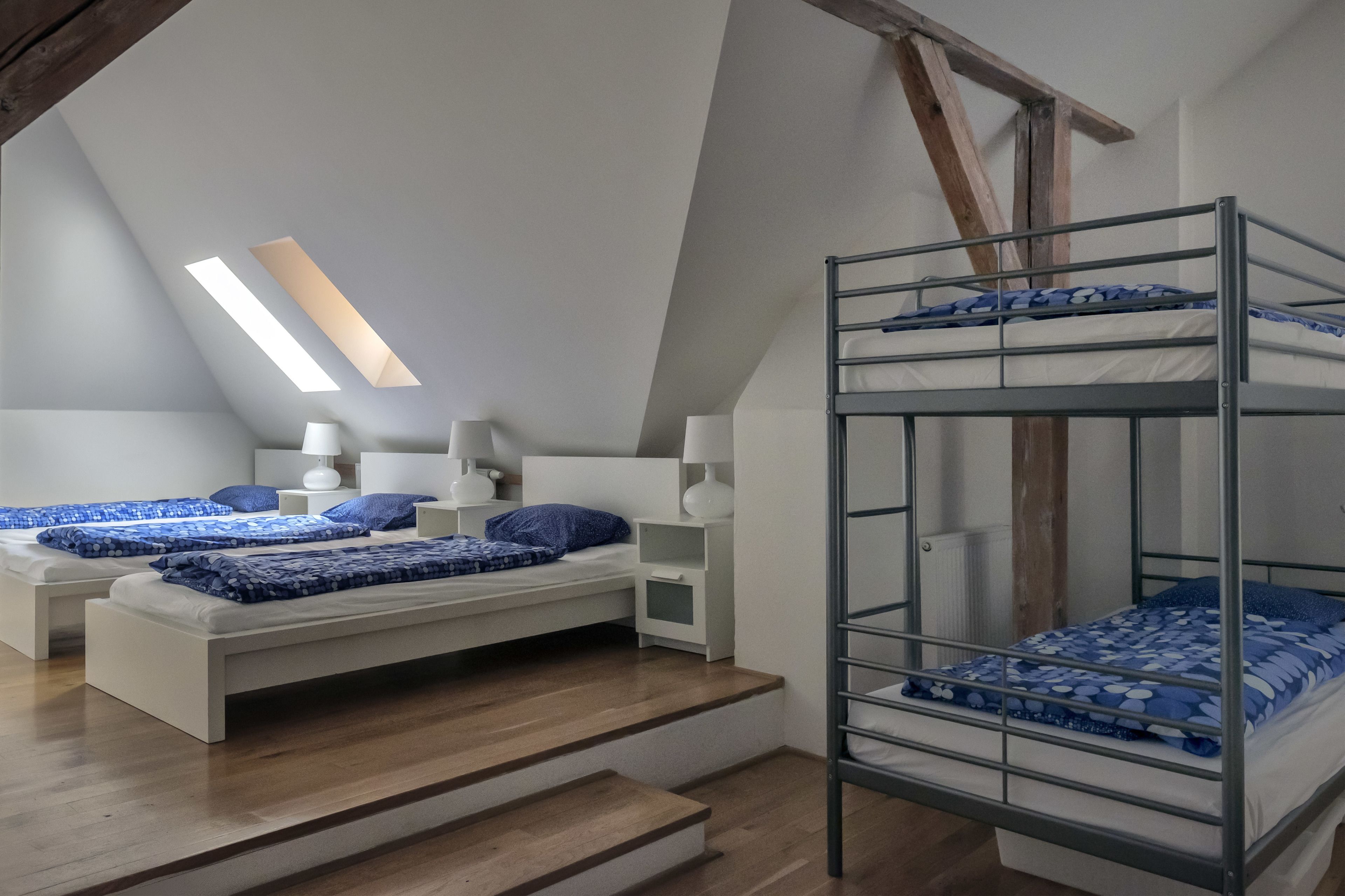 Une chambre de dortoir avec des lits superposés, un puits de lumière et une table de chevet blanche avec une lampe.