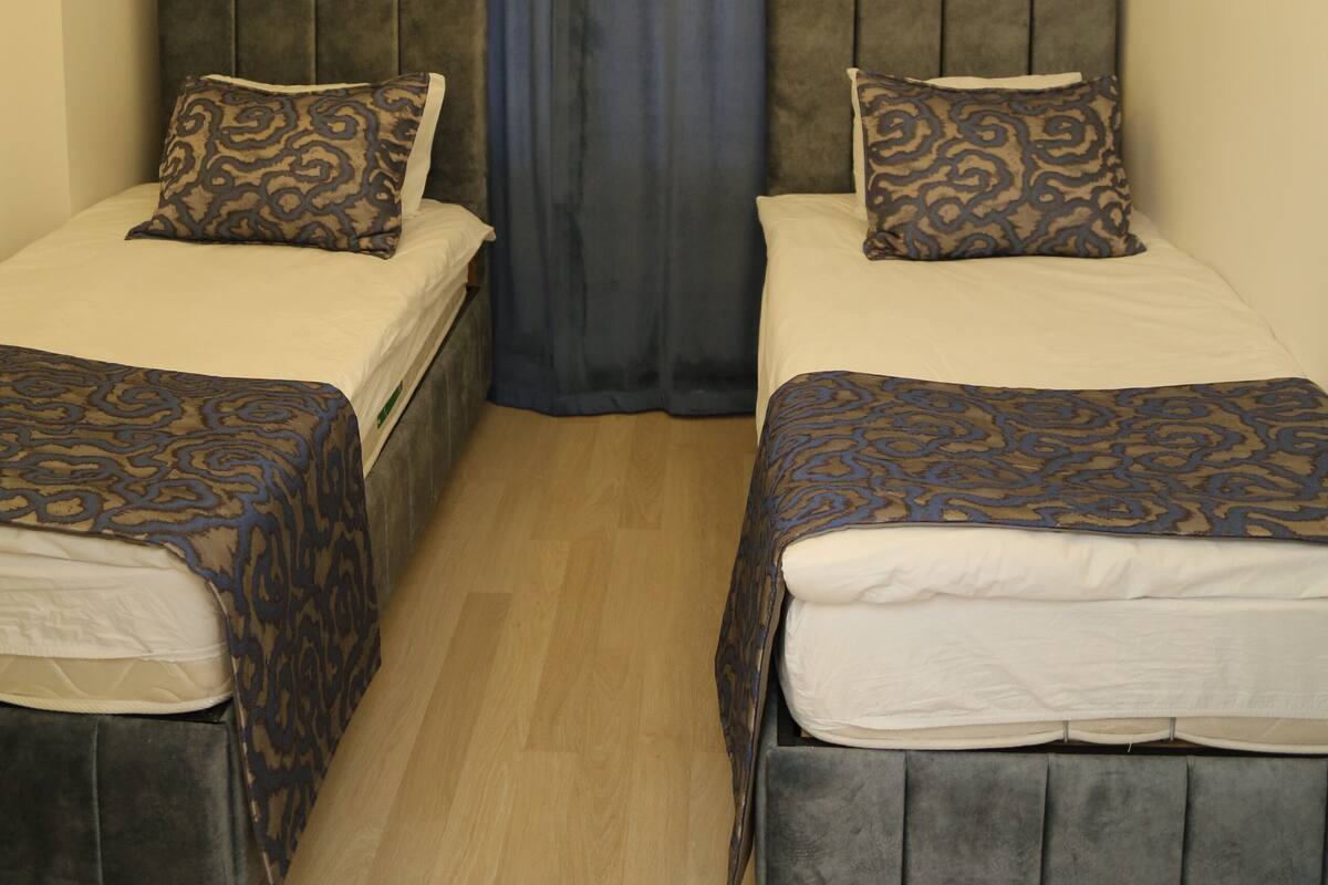 Une chambre d’hôtel avec deux lits, chacun doté d’une tête de lit et d’une couvre-lit à motifs.
