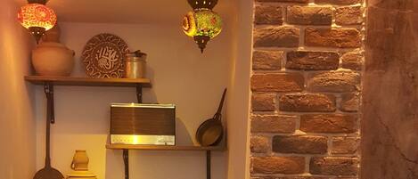 Una cocina con paredes de ladrillo visto, estantes con utensilios de cocina y un jarrón grande.