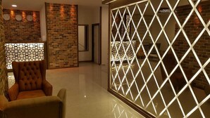 A modern interior with a brick wall, a cushioned armchair, and a decorative partition with geometric patterns.