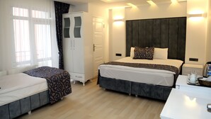 A modern hotel room with a large bed, a bedside table, a wardrobe, and a window with curtains.