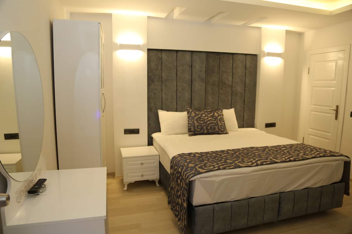 Une chambre à coucher avec un lit, des tables de chevet, une armoire et un miroir.