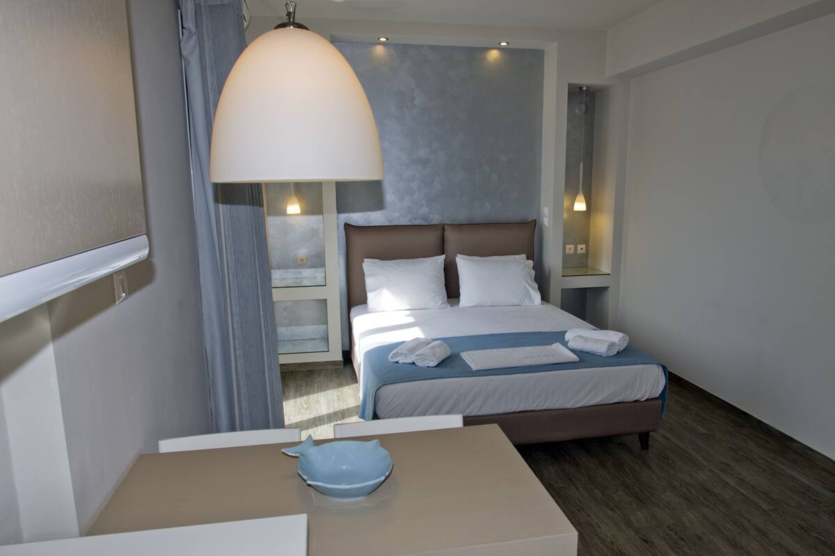 A hotel room with a large bed, bedside tables, a desk, and a bowl on the table.