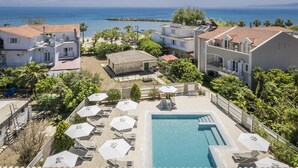A resort with a swimming pool, sun loungers, and a view of the sea. - Notos Luxury Studios (Kefalonia)