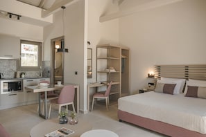 Quarto moderno com uma cama grande, uma escrivaninha e uma cadeira. Há uma pequena cozinha com fogão e armários.