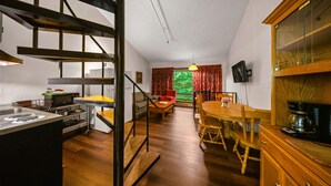 A compact kitchen with a dining area, wooden floors, and a view through a window. - Evergreen Valley Inn by Coolvacay (Stoneham)