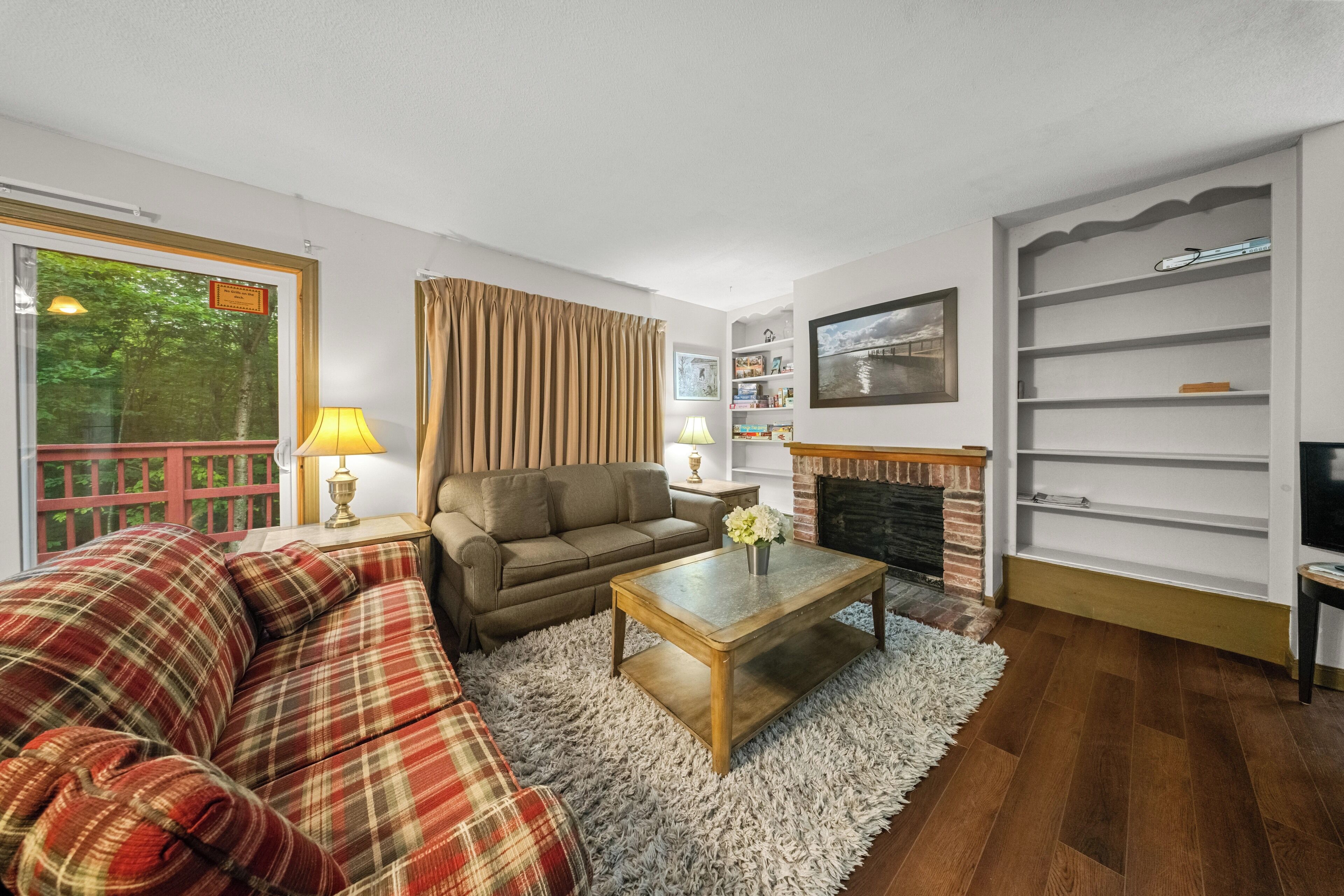 A living room with a sofa, armchair, and coffee table, a fireplace, and a bookshelf.