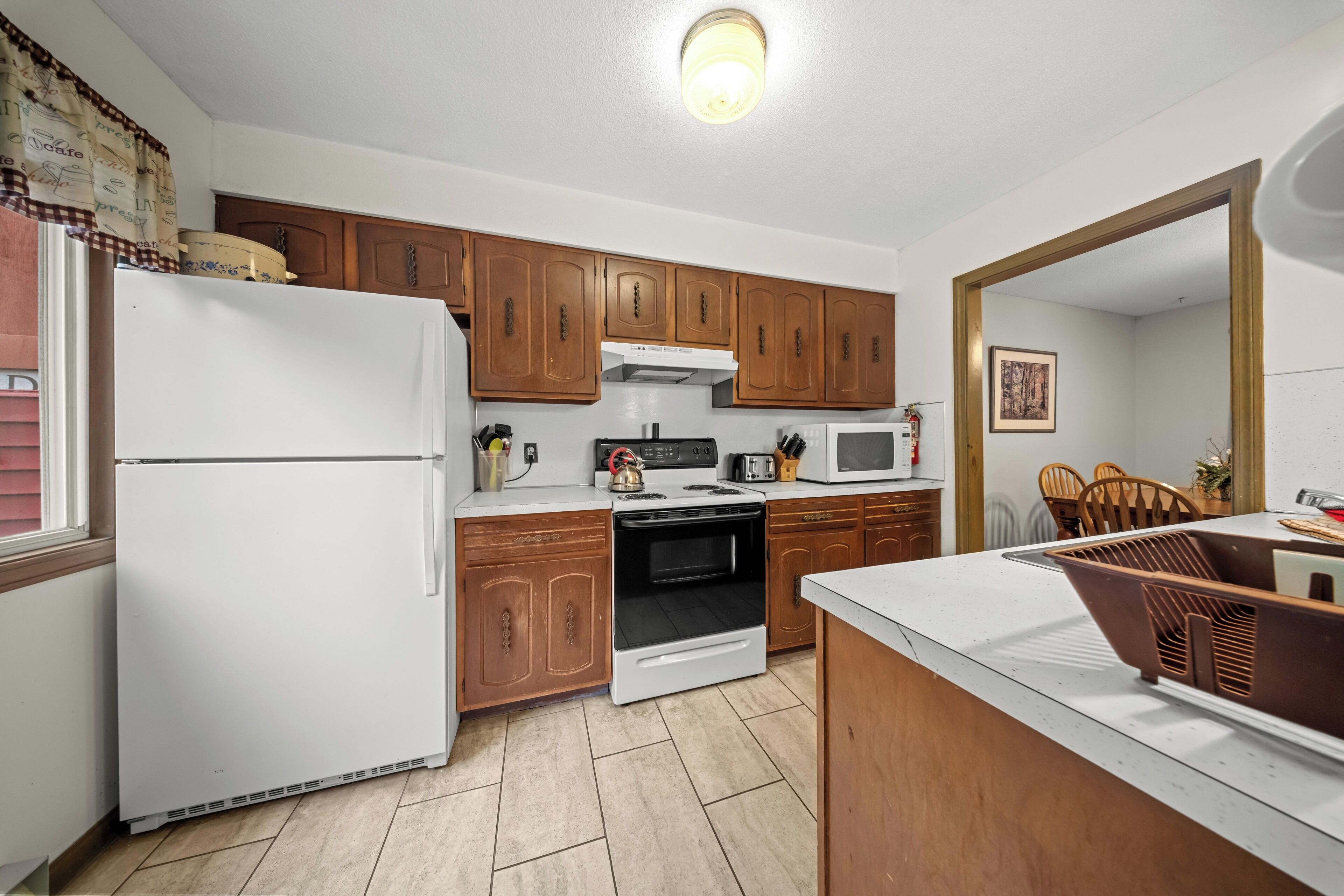 A compact kitchen with wooden cabinets, a white refrigerator, a stove, and a microwave.