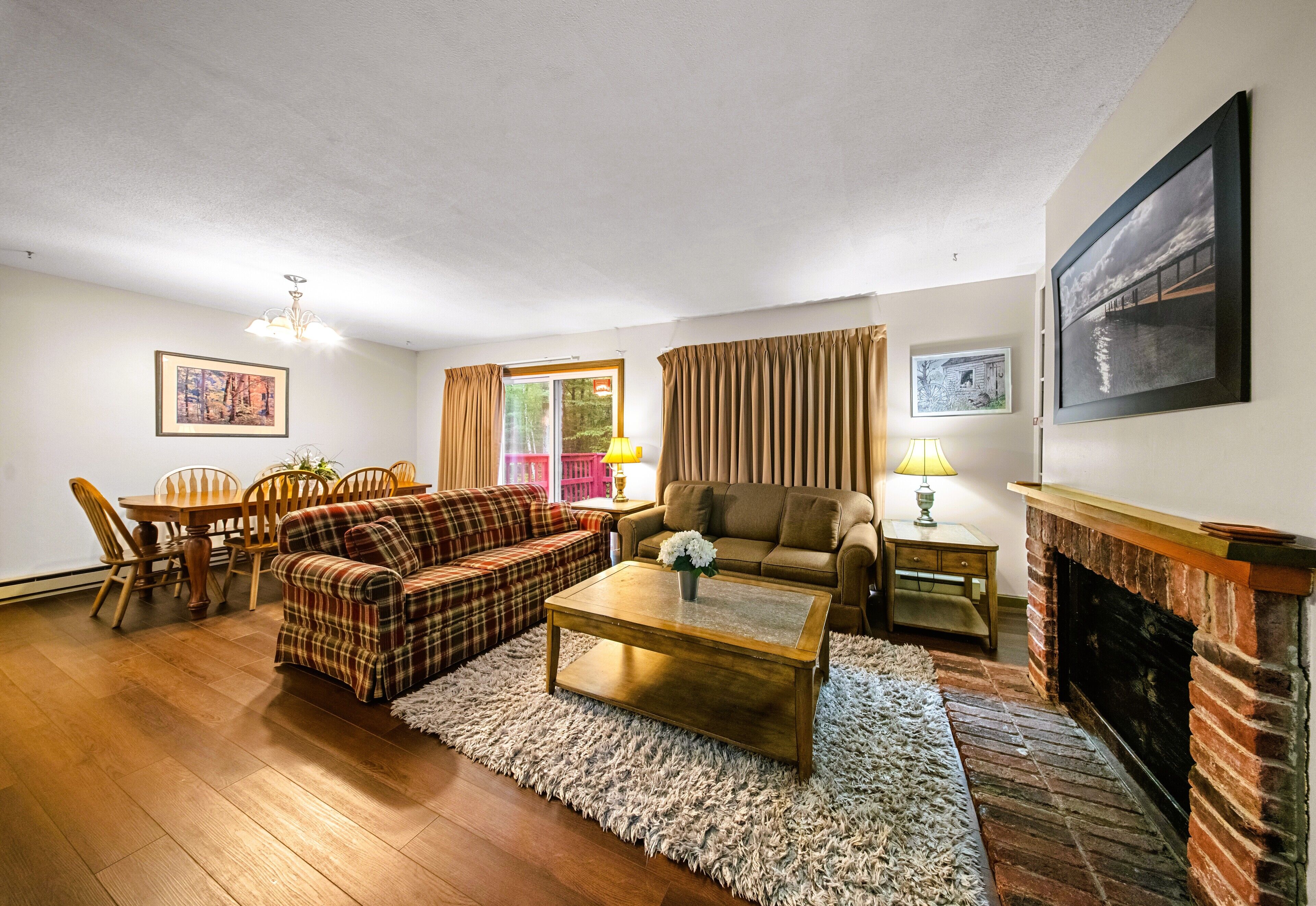 A living room with a fireplace, a dining table with chairs, a sofa, and a coffee table.