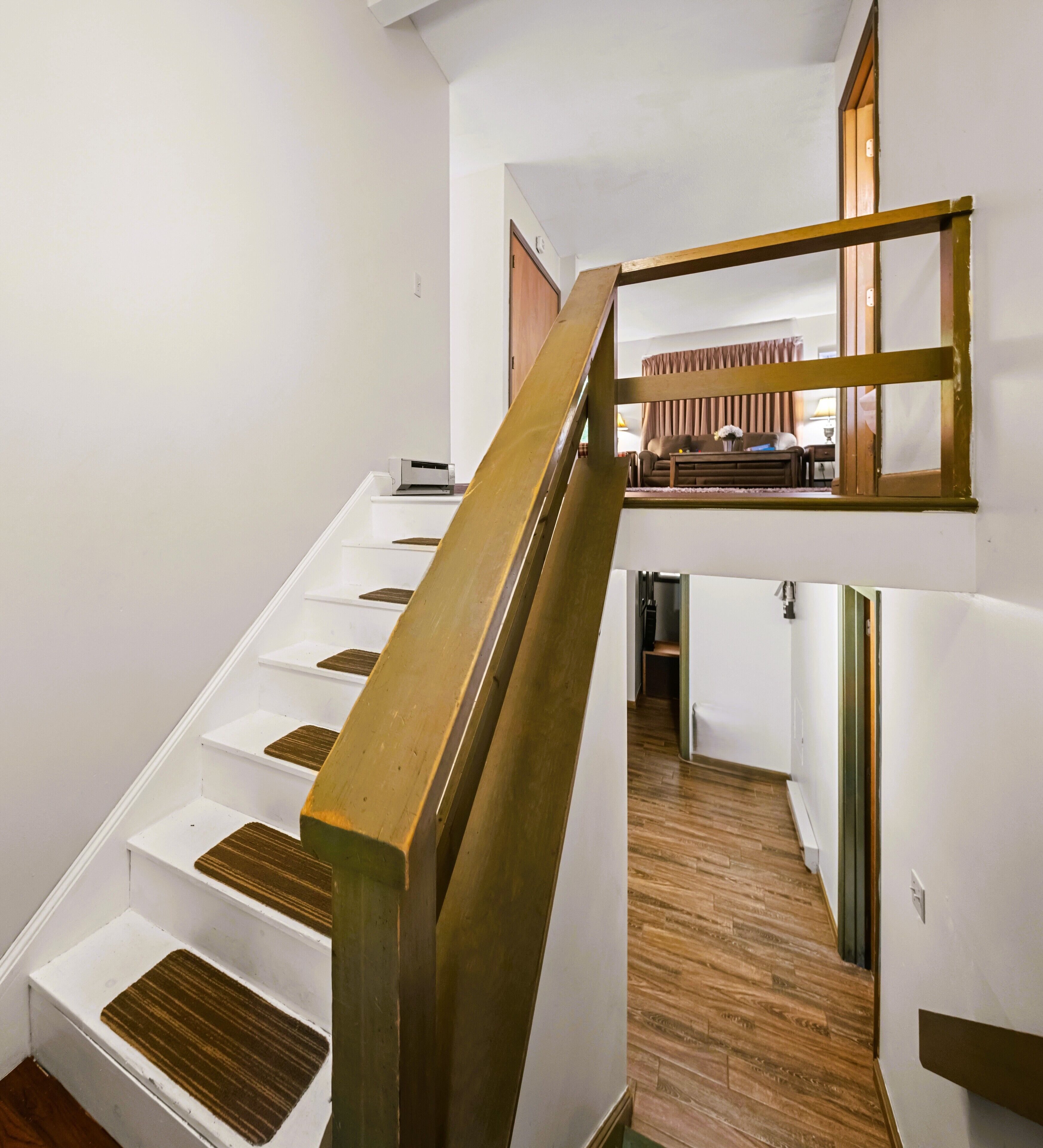 Una escalera de madera con barandilla metálica que conduce a un rellano en el segundo piso.