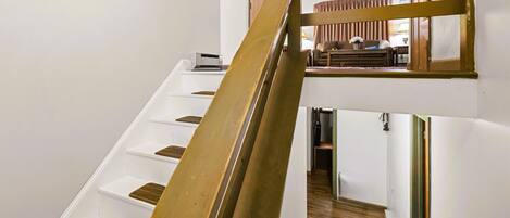 A staircase with wooden steps and a metal handrail leading to a second-floor landing.