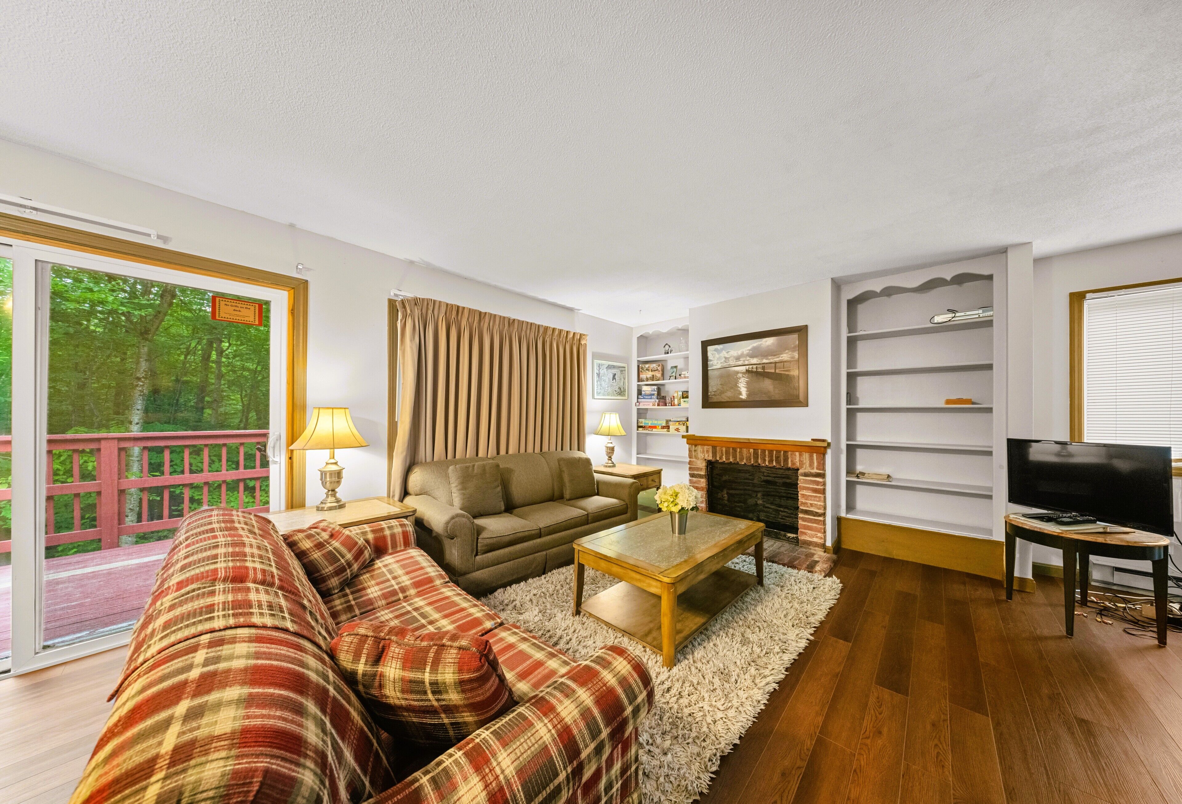 Una sala de estar con sofá, mesa de centro, chimenea, televisor y estantería.