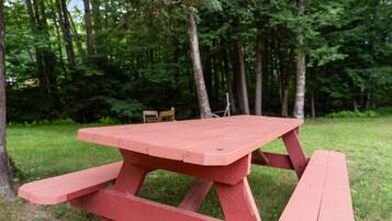A red picnic table in a grassy area with trees in the background.