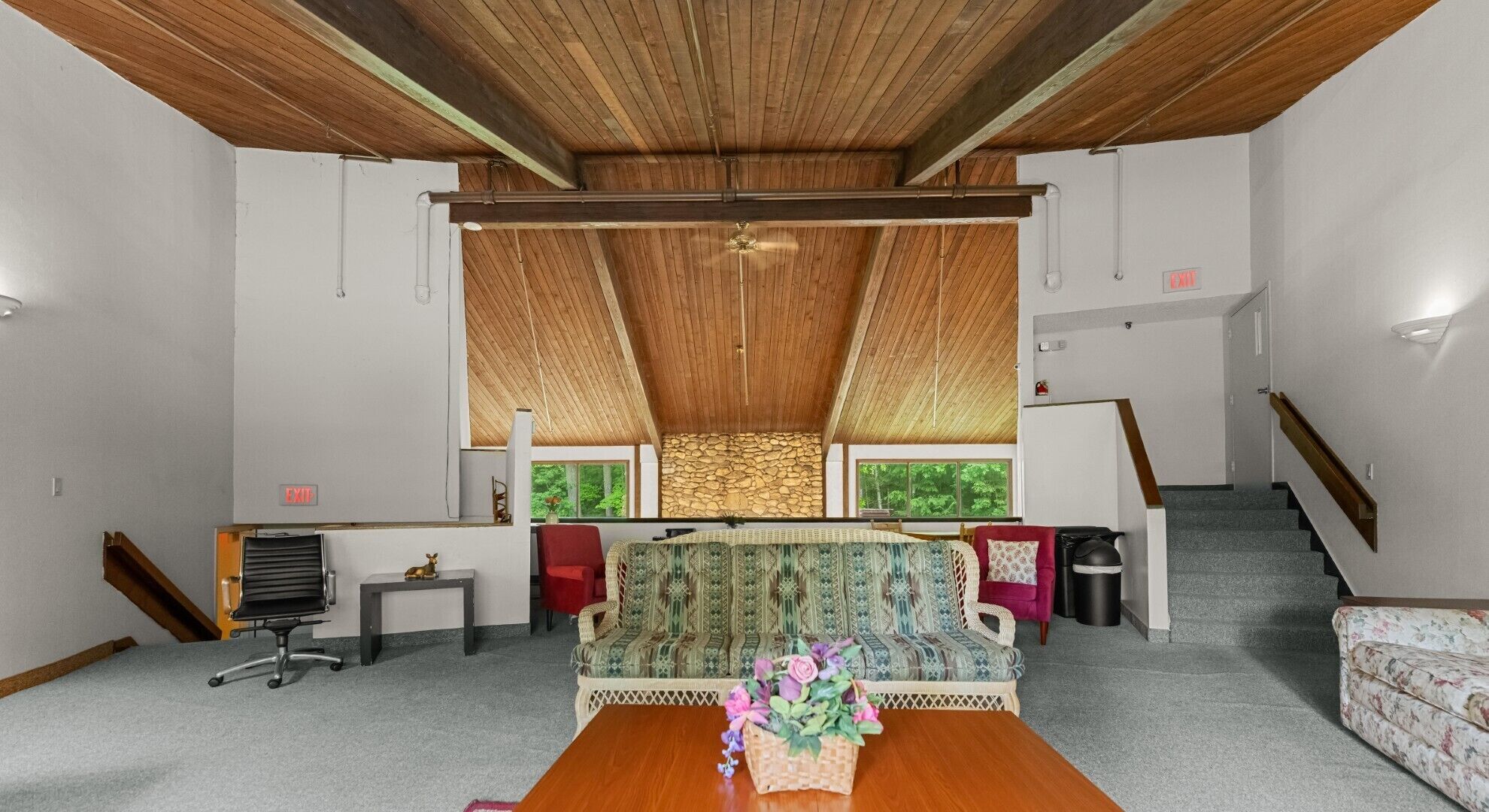Amplia habitación con techo alto, pared de piedra, un sofá, una mesa de centro y una escalera.