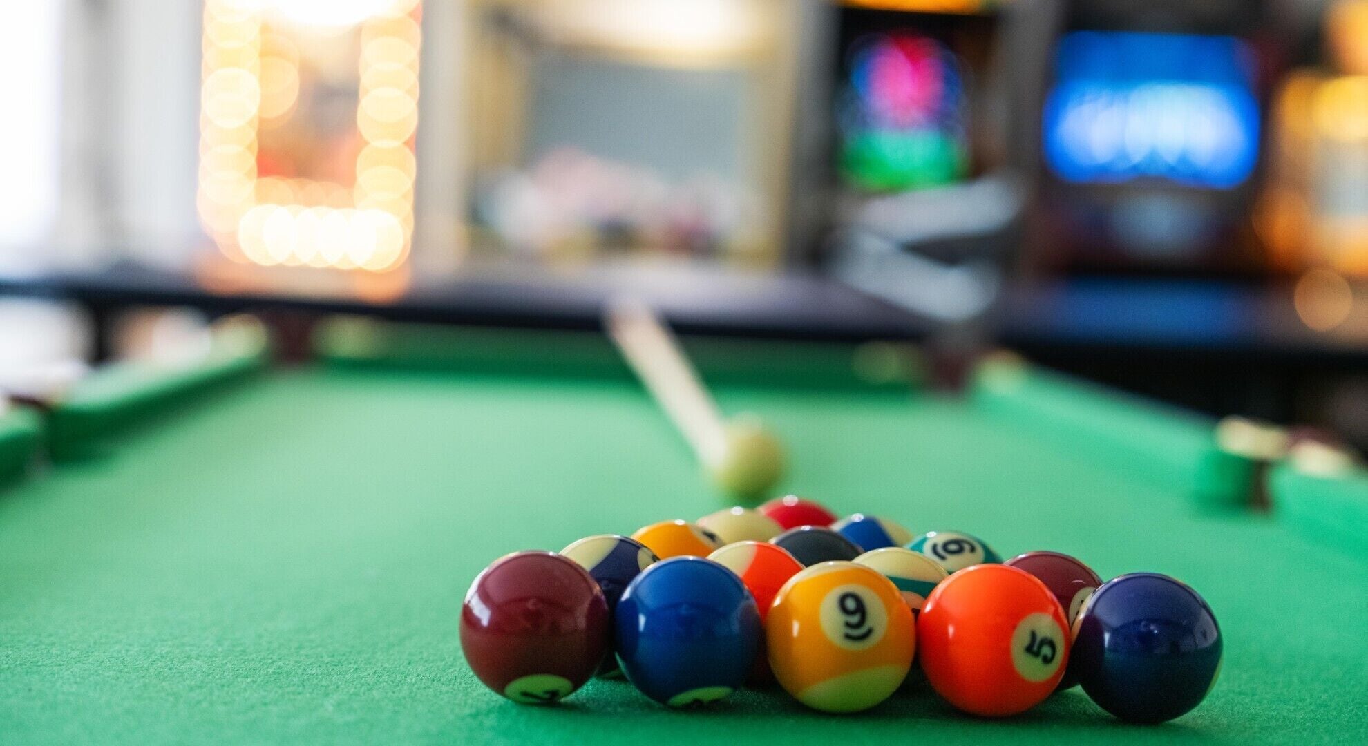 A close-up of a pool table with a cue stick and numbered billiard balls.