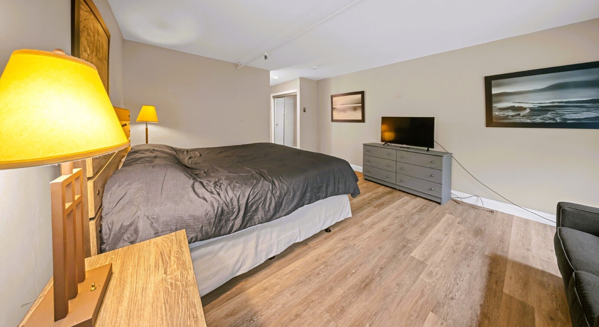 Une chambre à coucher avec un lit, deux lampes de chevet, une commode, un téléviseur et un tableau accroché au mur.