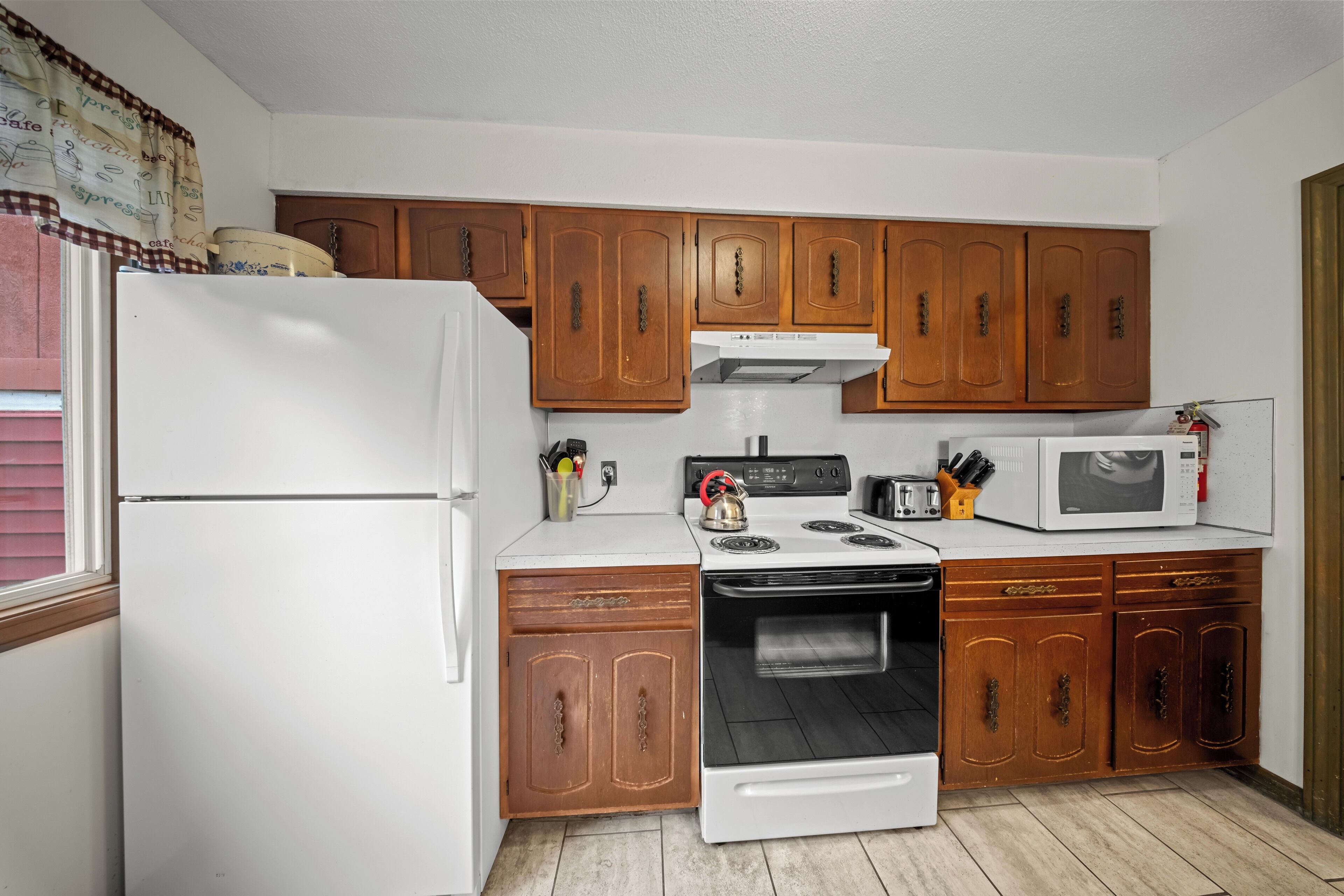 A kitchen with wooden cabinets, a white refrigerator, a stove, and a microwave.