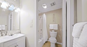 A modern bathroom with a white vanity, a shower, and a toilet.