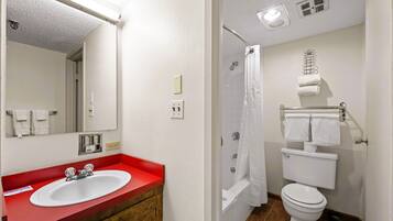 A bathroom with a red sink, white toilet, and shower curtain.