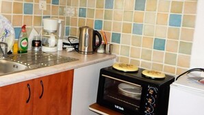 Een kleine keuken met een magnetron, waterkoker en koffiezetapparaat op het aanrecht.