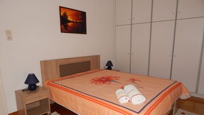 Een slaapkamer met een houten bed, twee nachtkastjes, een wandlamp en een schilderij.