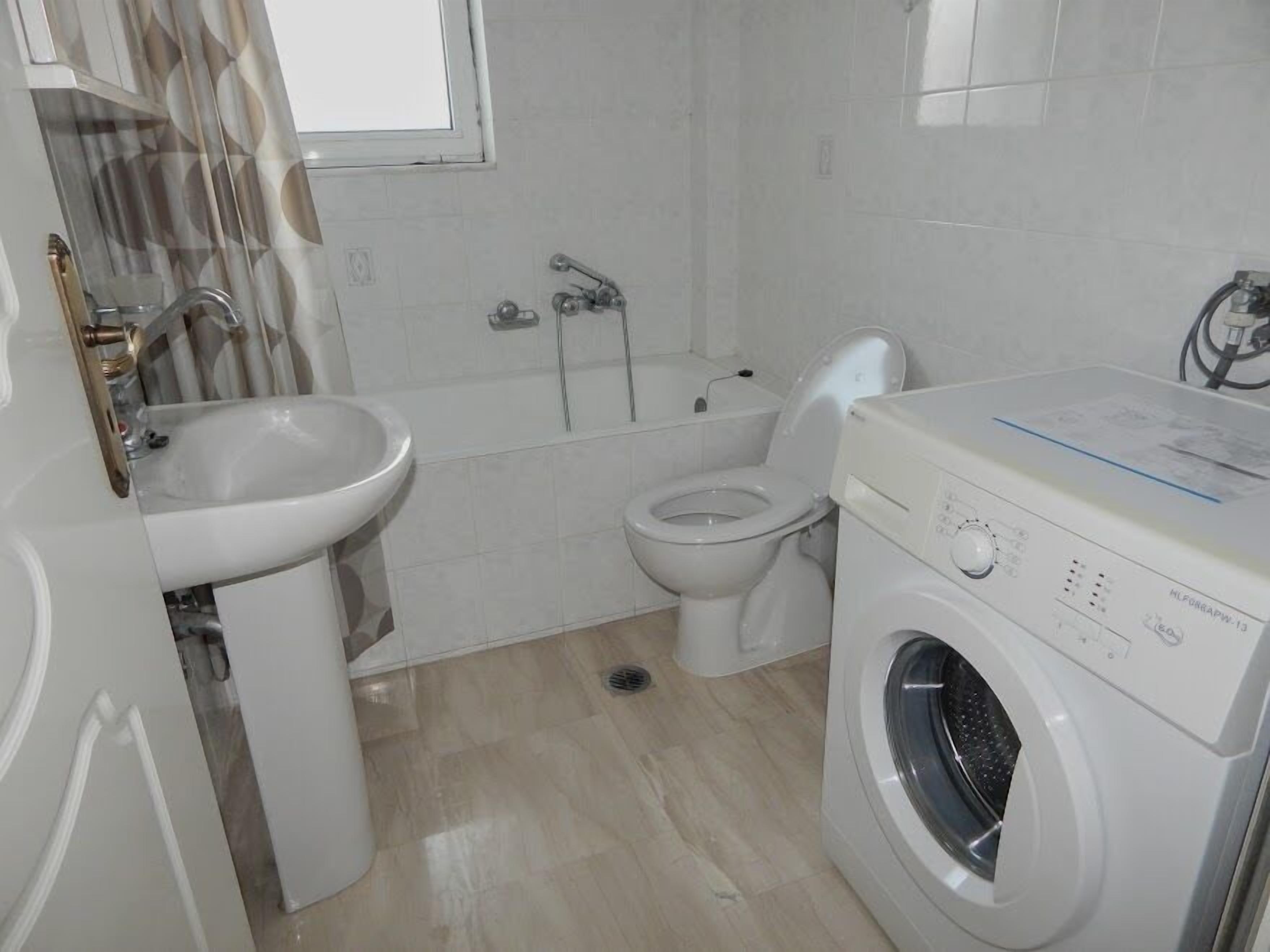 Ein Badezimmer mit Waschbecken, Toilette, Badewanne und Waschmaschine.