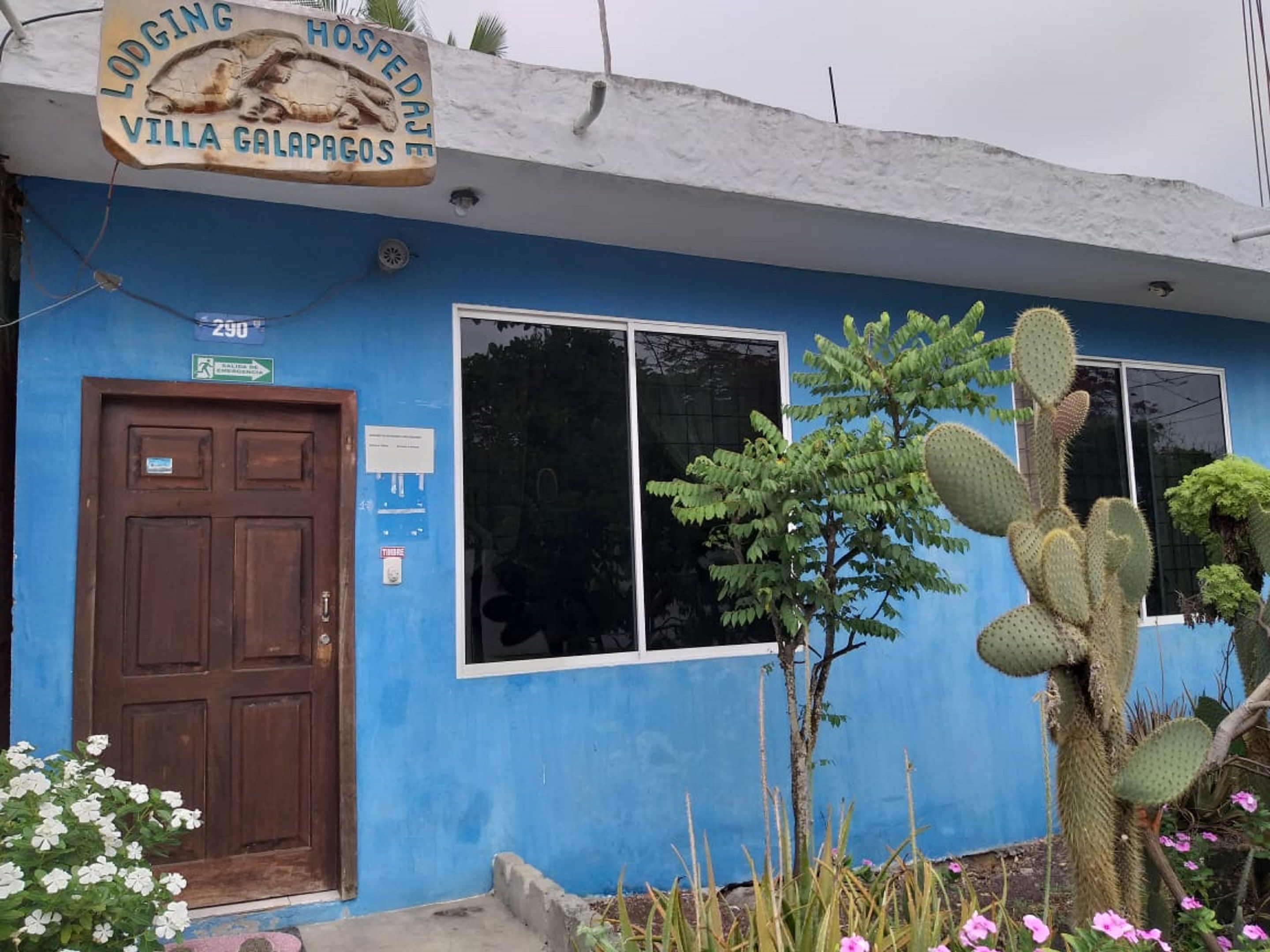 Un edificio con fachada azul, una puerta de madera y un letrero que dice "Lodging Hospedaje Villa Galapagos".