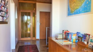 Ein Empfangsbereich mit einem Holztisch, einer Karte an der Wand und einer Bücherwand mit unterschiedlichen Büchern.