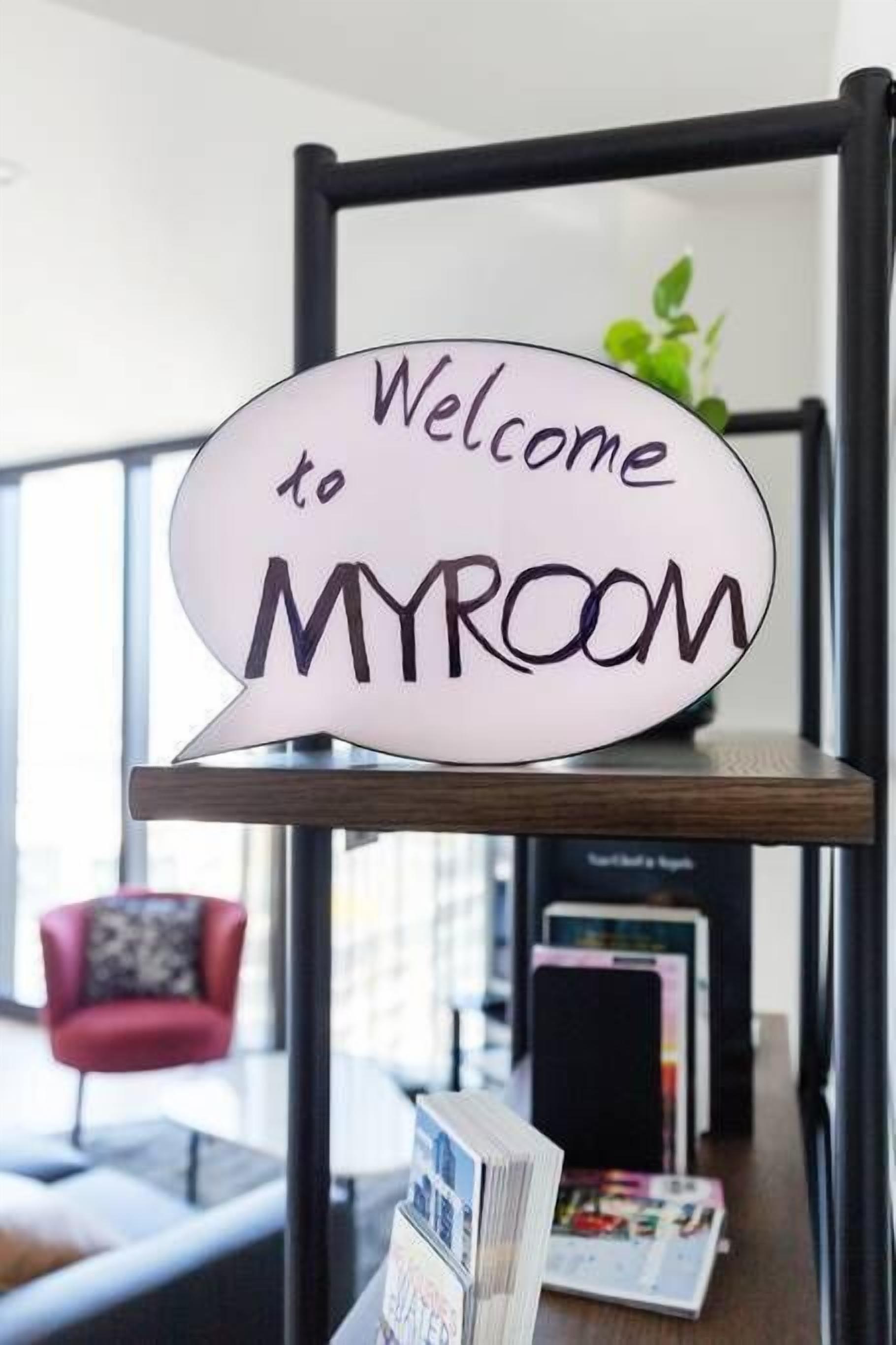 A speech bubble-shaped sign with the text "Welcome to MYROOM" on a shelf.
