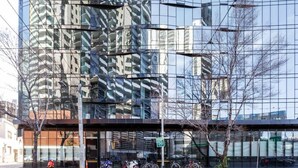 En moderne bygning med en reflekterende glasfacade, en overdækket indgang og et skilt, der viser "END 50".