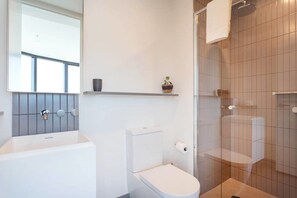 A modern bathroom with a bathtub, toilet, and shower area. - MYROOM at ShadowPlay (Southbank)
