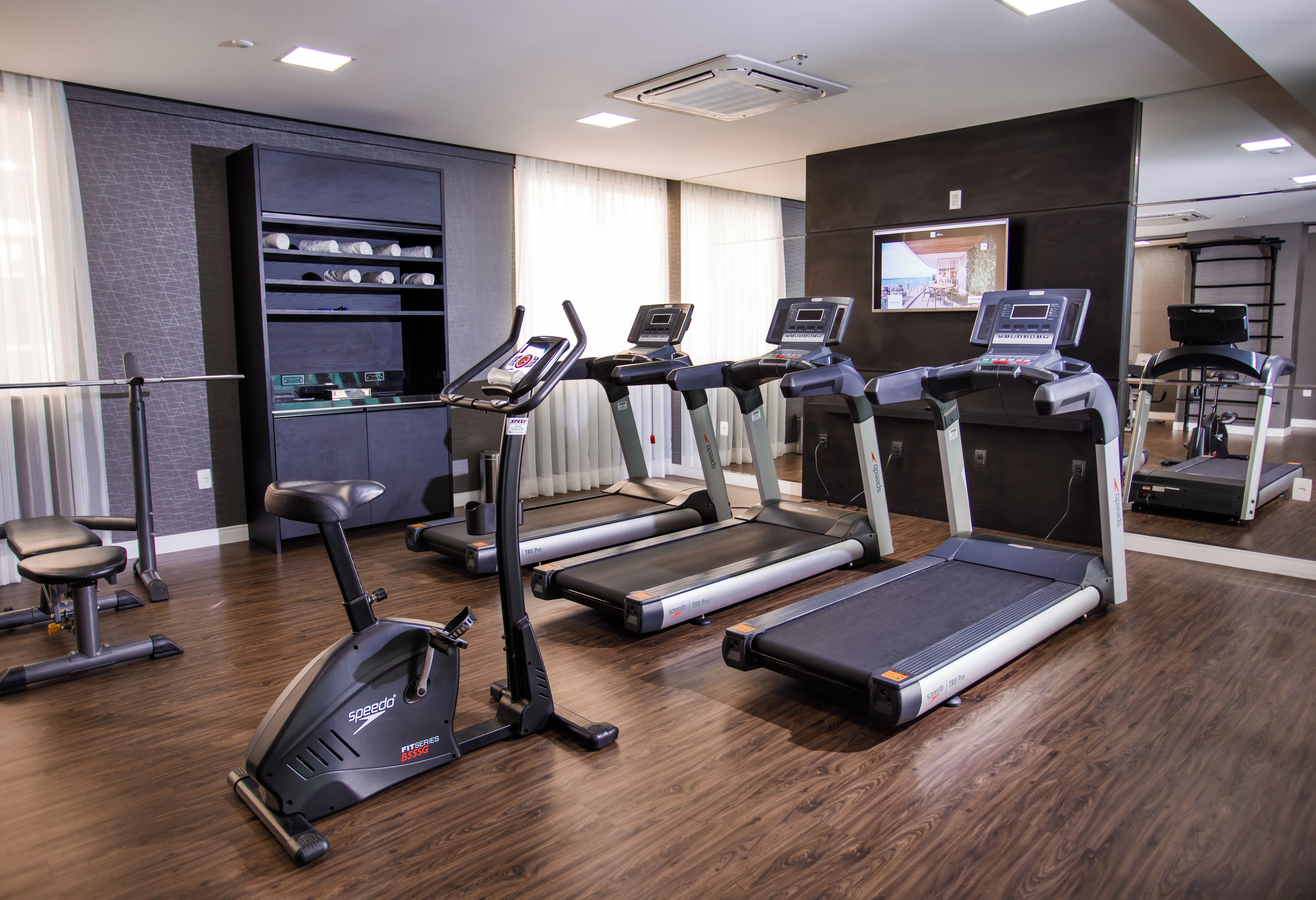 Un gimnasio con cintas de correr, una elíptica y una banca de pesas.