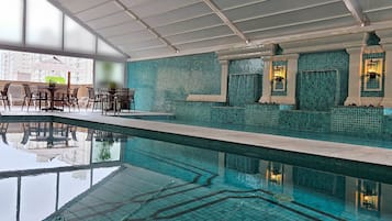 Una piscina techada, una piscina al aire libre, sombrillas