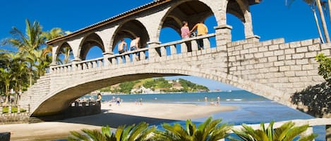 A stone bridge with arches over a beach.