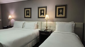A hotel room with two beds, nightstands, lamps, and three framed awards on the wall. - Sofistic Hotel (Itapema)
