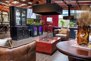 A modern lounge area with leather seating, a glass coffee table, and a cabinet with glass doors. - Sofistic Hotel (Itapema)