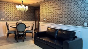 A room with a dining table, chairs, a black leather sofa, and patterned wallpaper. - Sofistic Hotel (Itapema)