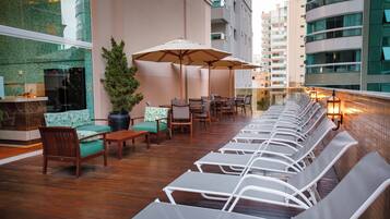 A rooftop lounge area with seating, a potted plant, and a view of the cityscape.