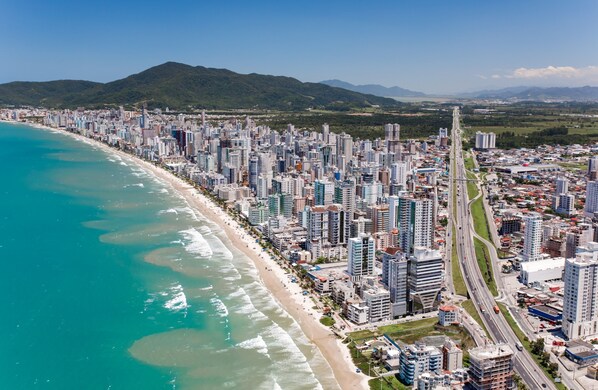 Un paisaje urbano costero con playa, edificios altos y una autopista.