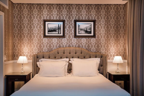 A hotel room with a large bed, two framed pictures on the wall, and two bedside lamps. - Sofistic Hotel (Itapema)