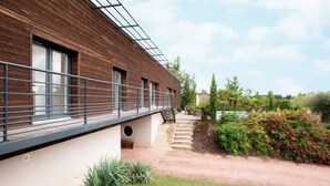 Ein modernes Gebäude mit Holzfassade, einem überdachten Gang und einem angelegten Garten mit Pool.