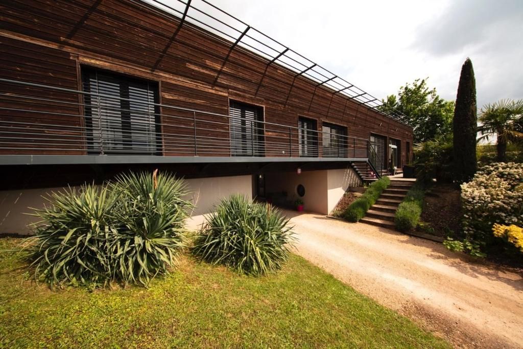A modern building with a sloped roof, a covered walkway, and a gravel driveway.