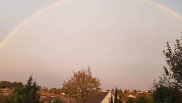 A residential area with houses and trees, a rainbow in the sky, and a clear horizon.