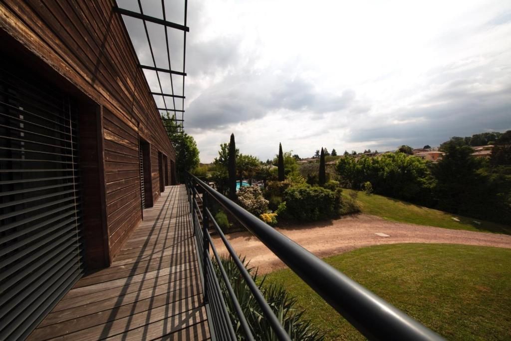 Een balkon met uitzicht op een aangelegde tuin en verre heuvels.